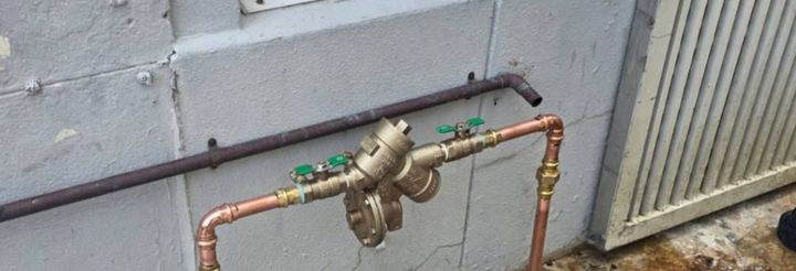 New copper backflow preventer installed on an exterior wall